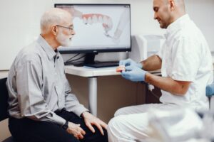 Handsome old man talking to the dendist. Two man in the dentist's office
