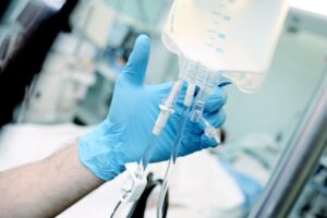 Male medical worker regulate the intravenous drip system at the patient bed in the critical care unit.